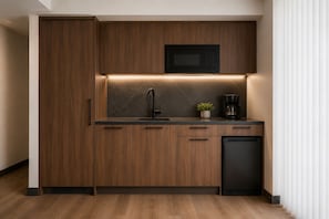 Eine moderne Küche mit Holzschränken, einer eingebauten Mikrowelle, einem Spülbecken und einer Kaffeemaschine.