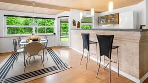 Una cocina moderna con techo de madera, ventanas amplias y una barra con taburetes.