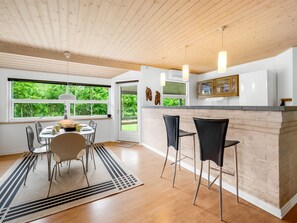 A modern kitchen with a wooden ceiling, large windows, and a bar area with stools. - "Nane" - 600m to the fjord by Interhome (Skjern)