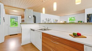 Una cocina moderna con armarios blancos, cajones de madera, lavavajillas integrado e iluminación colgante.