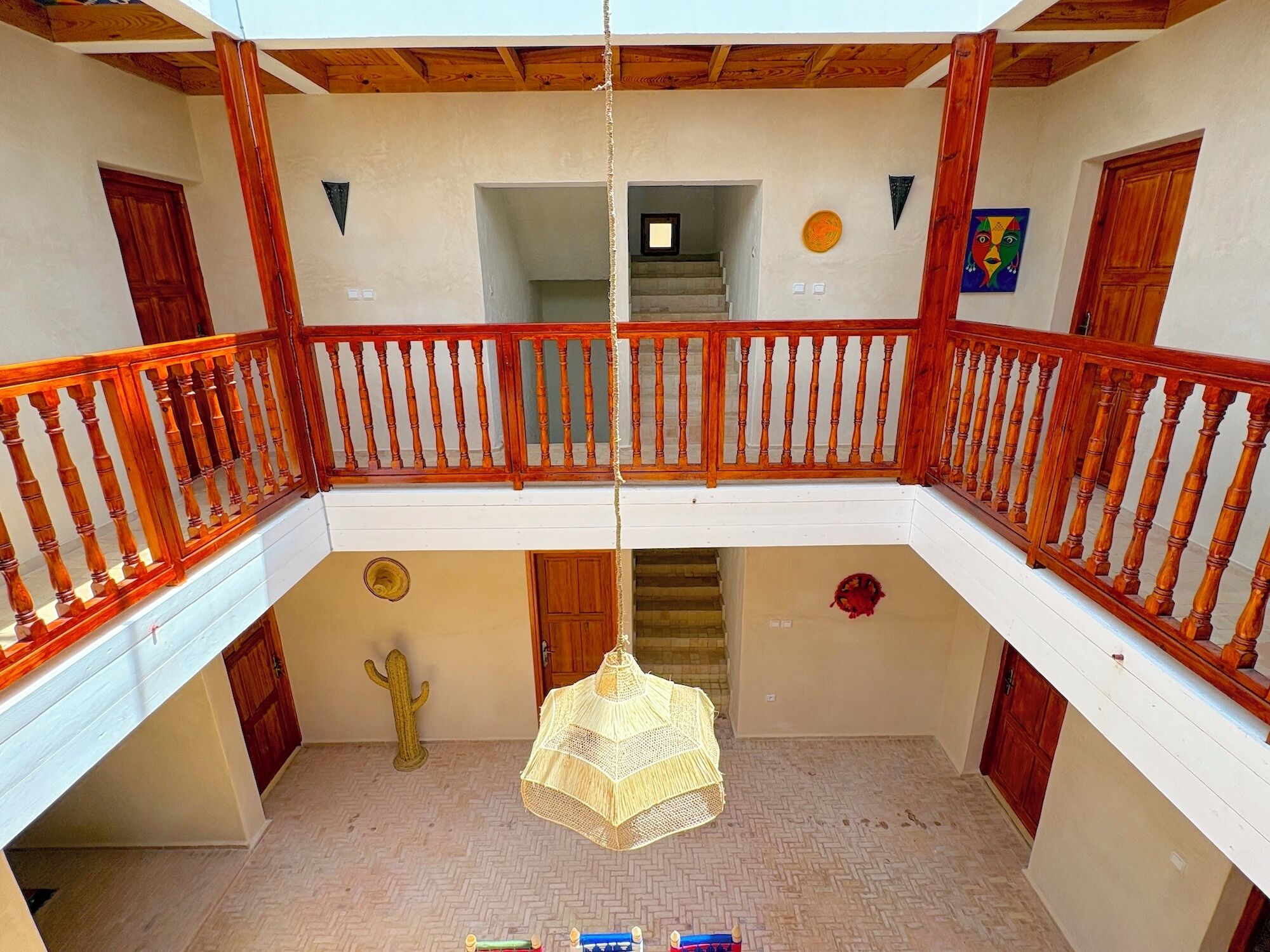 Un intérieur spacieux agrémenté d’une balustrade en bois, d’un luminaire suspendu et d’une décoration à base de cactus.