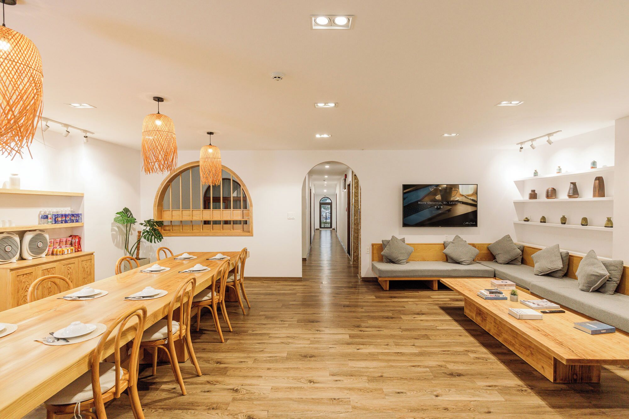A modern interior with a dining area, a sofa, and a hallway leading to another room.