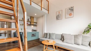 A modern living space with a staircase, a sofa, a small table, and a kitchen area. - HAKU Boutique Hotel Da Lat - Ngo Quyen (Cam Ly - Da Lat)