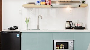 A modern kitchen with a built-in refrigerator, a microwave, and a kettle on the countertop. - HAKU Boutique Hotel Da Lat - Ngo Quyen (Cam Ly - Da Lat)