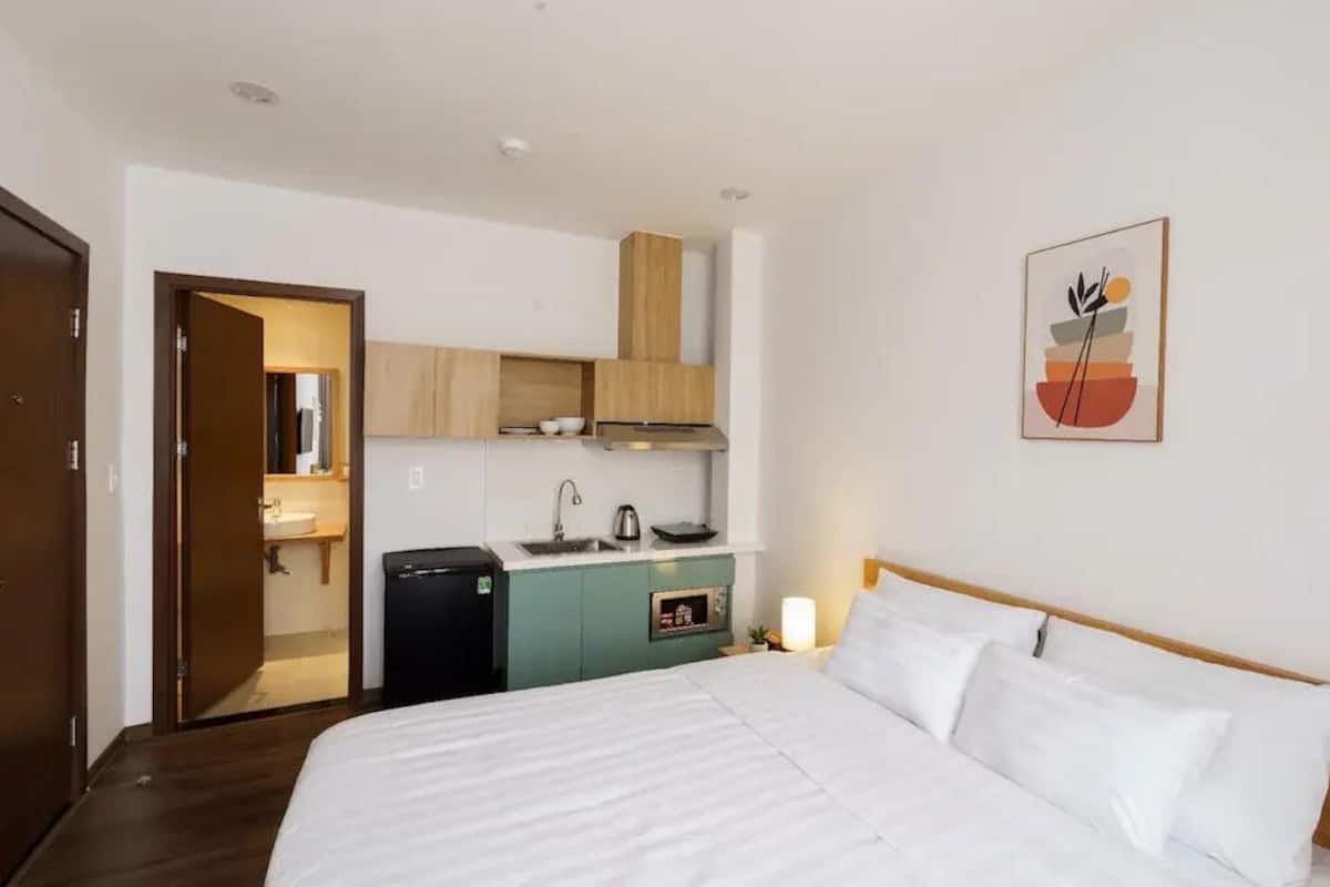 Ein Hotelzimmer mit Bett, einer Küchenzeile und einer Tür zu einem Badezimmer.