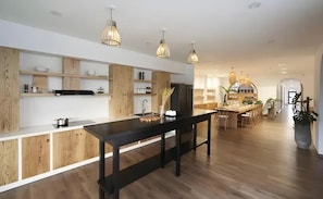 Eine moderne Küche mit Holzschränken, einer schwarzen Arbeitsplatte und Pendelleuchten.