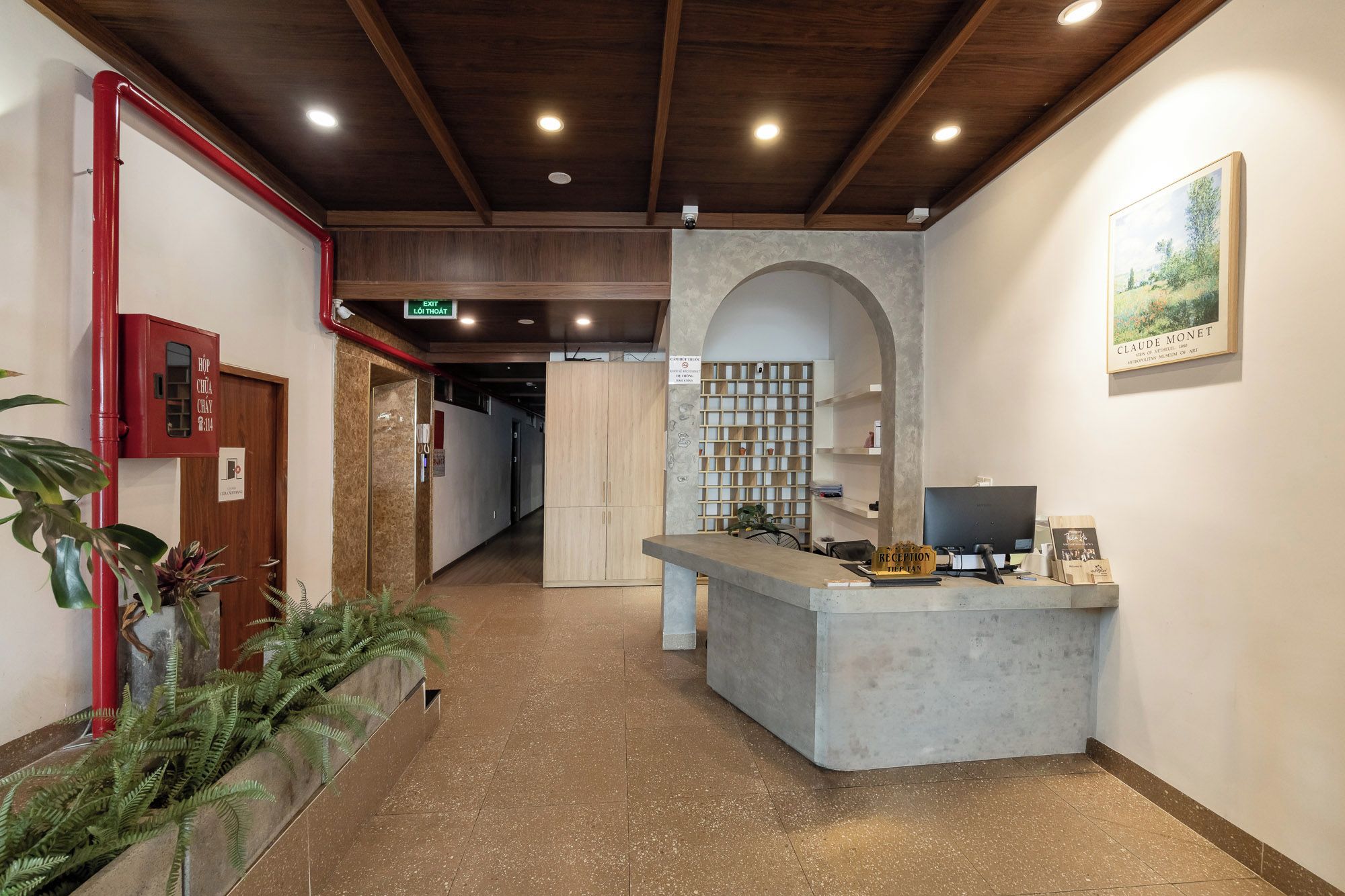 A reception area with a reception desk, a sign indicating an exit, and a wall-mounted painting.