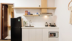 A compact kitchen with a black refrigerator, a microwave, and a stove. - HAKU Boutique Hotel Da Lat - Ngo Quyen (Cam Ly - Da Lat)