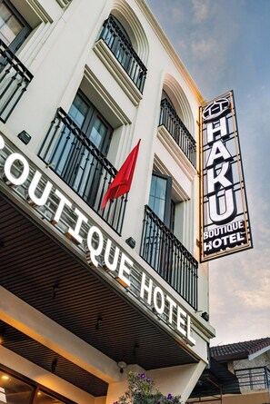 Een hotelschilt met 'BOUTIQUE HOTEL' en een rode vlag op het balkon.