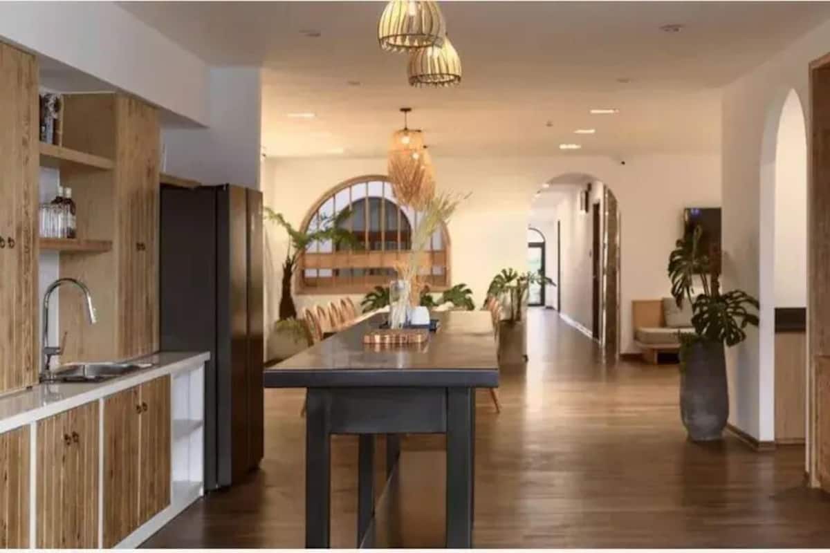 Eine moderne Küche mit Holzschränken, einer zentralen Kochinsel und Pendelleuchten.
