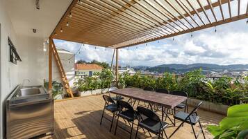 An outdoor patio with a table and chairs, a sink, and a view of a cityscape.