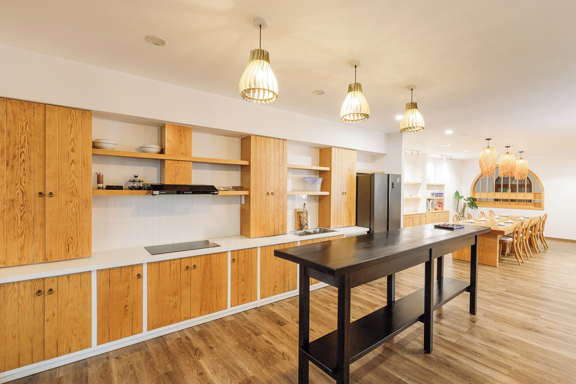 Cocina moderna con gabinetes de madera, una isla central e iluminación colgante.