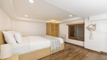 A bedroom with a bed, wooden wardrobe, and a window with a macrame decoration.