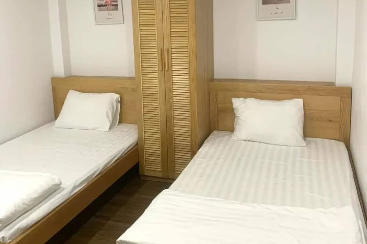 Ein Zimmer mit zwei Einzelbetten, einem Holzschrank und zwei gerahmten Bildern an der Wand.