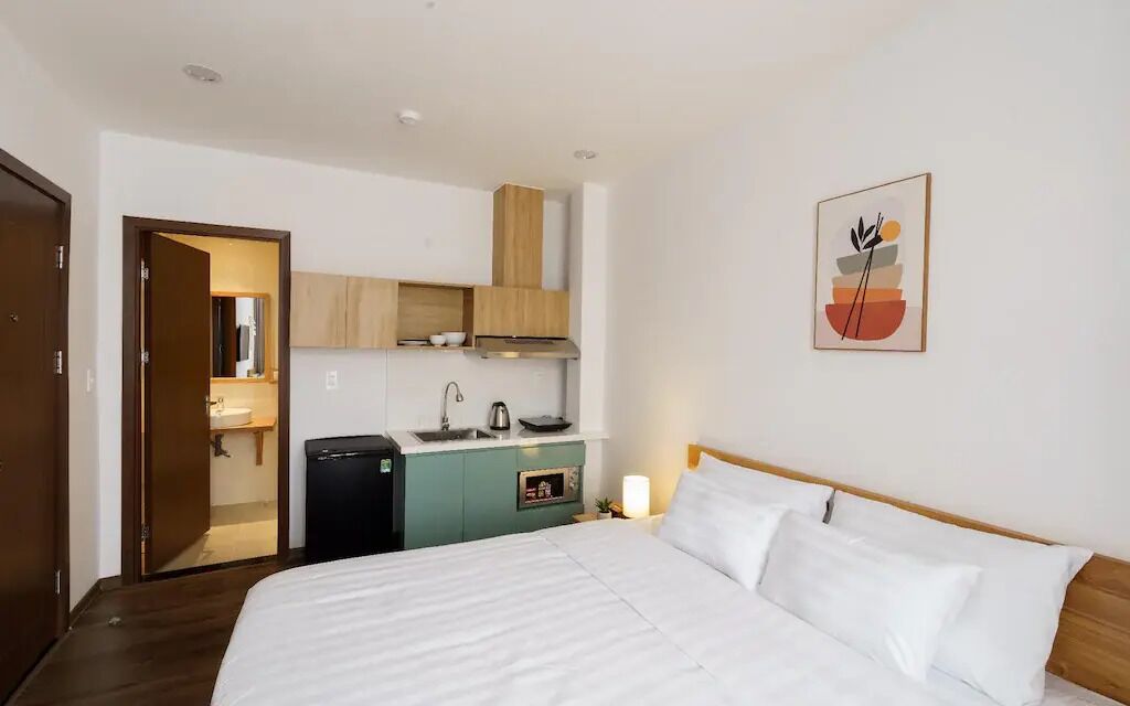 Een hotelkamer met een bed, een kitchenette en een deur naar een badkamer.