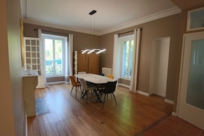 A dining area with a table and chairs, large windows, and a radiator. - 200-square-meter apartment in Villa Tamaris, Aix-les-Bains (Aix-les-Bains)