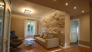 Ein Wohnzimmer mit Sofa, Sessel, Couchtisch und einer großen Wandmalerei.
