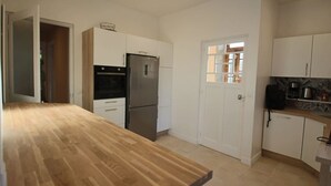 Eine Küche mit Holzarbeitsplatte, weißen Schränken, einem Edelstahlkühlschrank und einer Tür mit Fenster.