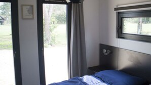 Een slaapkamer met een bed, een raam, een deur en een wandlamp.