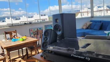 Um toca-discos Pioneer numa mesa de madeira em um quarto iluminado pelo sol, com janelas grandes, um sofá azul e uma bola de espelhos.