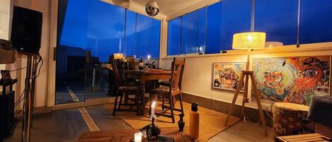 A cozy room with a wooden table, chairs, a small rug, and a painting on the wall.