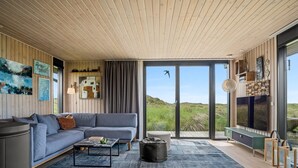A modern living room with a sofa, coffee table, and artwork on the walls. - "Beatrice" - 350m from the sea by Interhome (Pandrup)