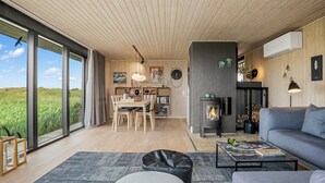 A spacious living area with a large window, a fireplace, and a modern kitchen. - "Beatrice" - 350m from the sea by Interhome (Pandrup)
