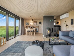 Ein großzügiger Wohnbereich mit großem Fenster, Kamin und moderner Küche.
