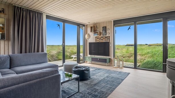 A modern living room with a sofa, coffee table, and TV, large sliding glass doors, and a wooden ceiling. - "Beatrice" - 350m from the sea by Interhome (Pandrup)