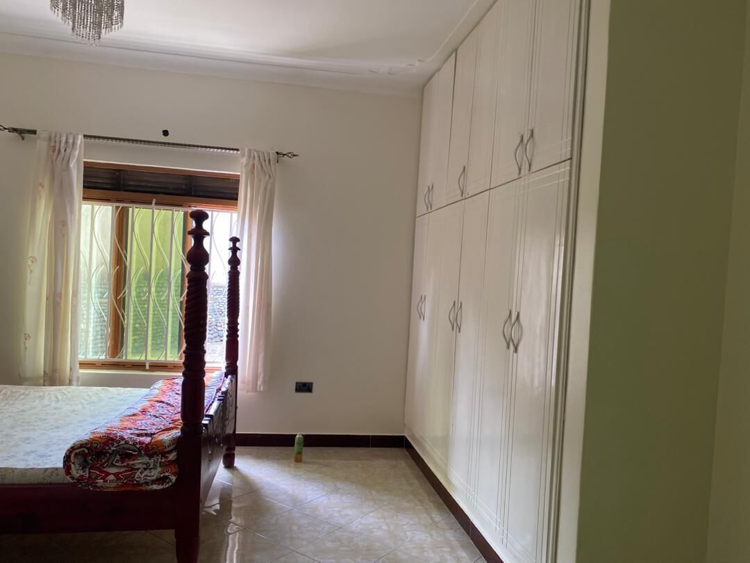Une chambre à coucher avec un lit, une fenêtre avec des rideaux, une armoire et un lustre.