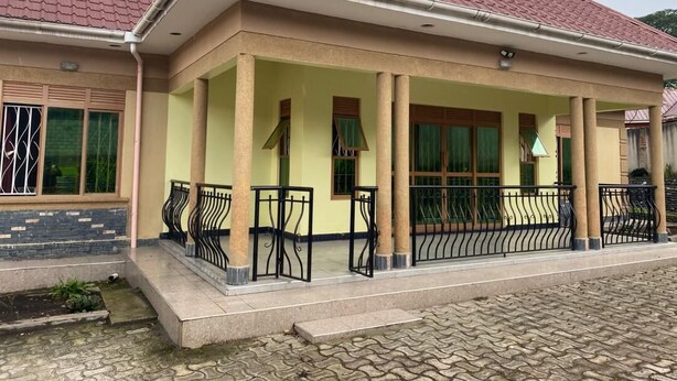 A two-story building with a tiled roof, a covered porch with columns, and a paved entrance area. - Peaceful 4-bedroom house in Fort Portal perfect for relaxing stays (Fort Portal)