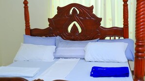A bed with a wooden headboard, white bedding, and a blue item on the bed. - Peaceful 4-bedroom house in Fort Portal perfect for relaxing stays (Fort Portal)