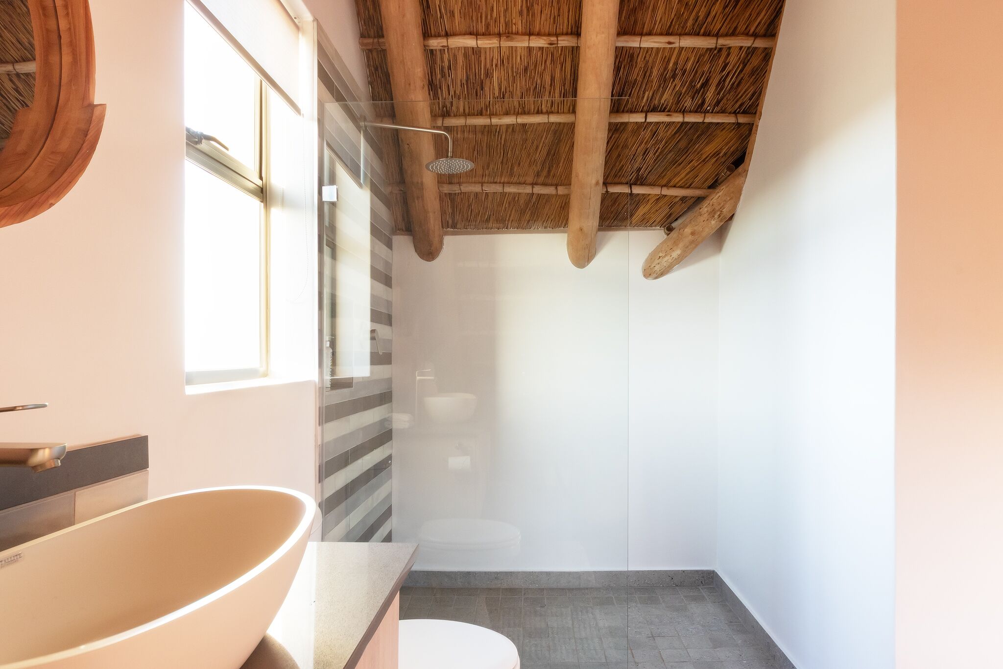 A bathroom with a large bathtub, a shower, a toilet, and a window.