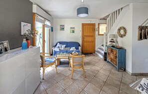 Ein Wohnzimmer mit einer Couch, einem Couchtisch und Sesseln. Eine Holztür und eine Treppe führen in einen anderen Raum.