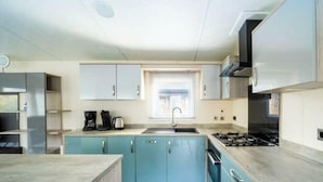 A modern kitchen with light blue cabinets, a central island, a window with blinds, and a stove. - Holiday Home in Otterlo With Terrace (Otterlo)
