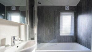 A modern bathroom with a large bathtub, a sink, and a mirror. - Holiday Home in Otterlo With Terrace (Otterlo)