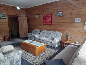 Una habitación acogedora con un sofá estampado, una mesa de centro de madera y un cartel rojo con una frase motivadora en la pared.