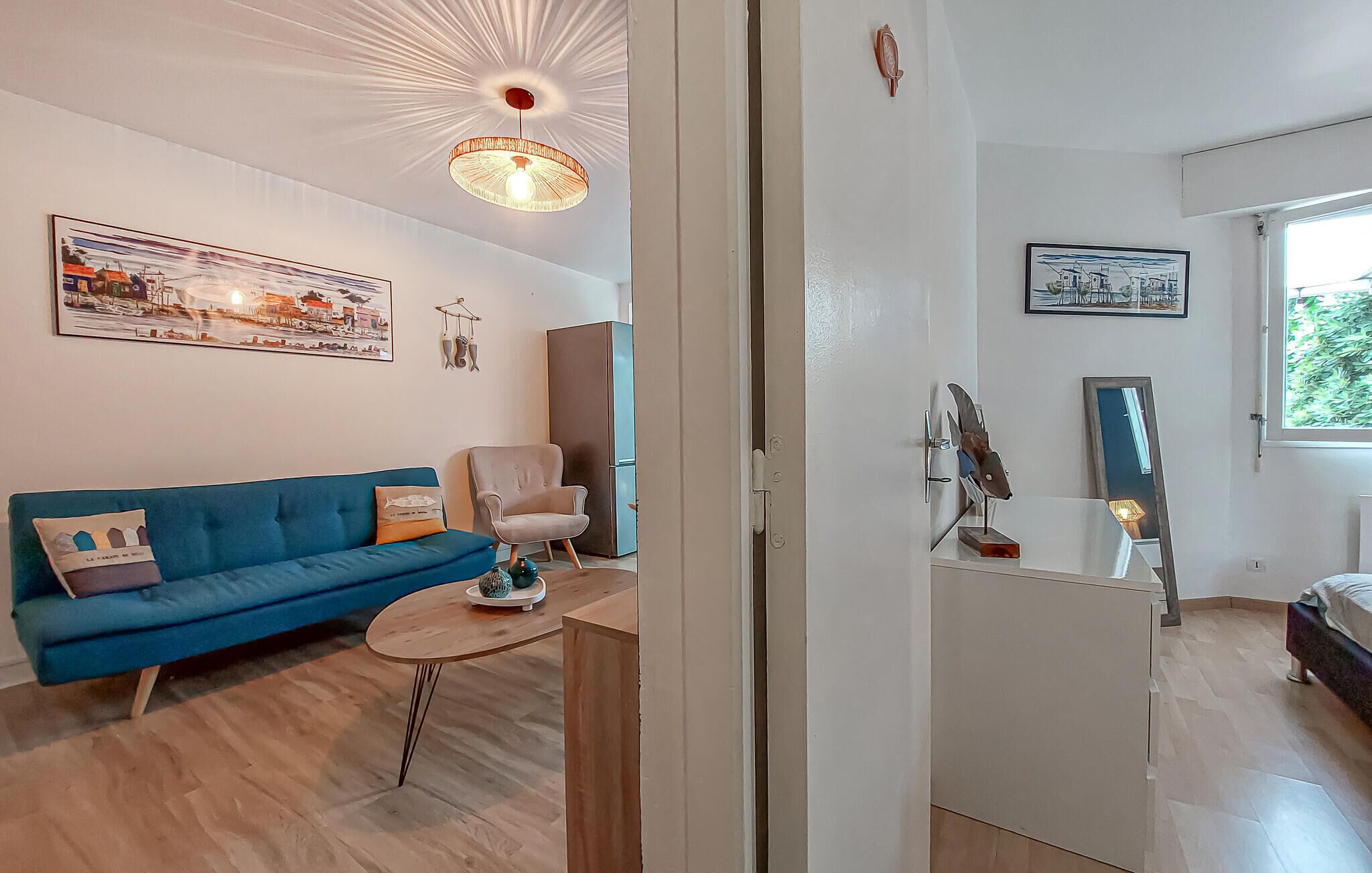 Uma sala de estar moderna com um sofá azul, uma pequena mesa redonda e uma porta que dá para outro quarto.