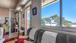 Une chambre avec vue sur la plage, un canapé, un fauteuil et une table avec une lampe.