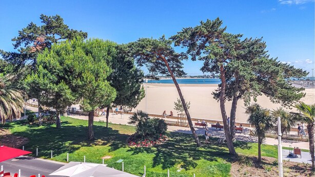 Un parc au bord de la plage, doté d’arbres, de bancs et offrant une vue sur la plage.
