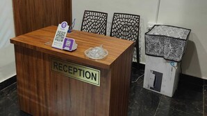 Un mostrador de recepción con un letrero, una puerta de madera, un armario empotrado y adornos decorativos en la pared.
