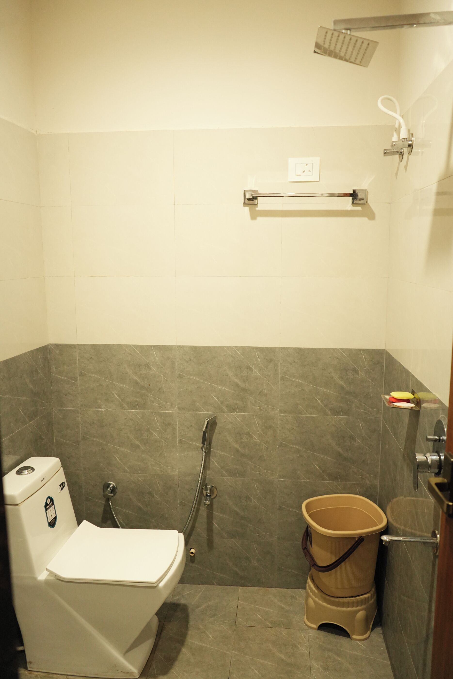 A small bathroom with a toilet, a shower, and a grab bar.