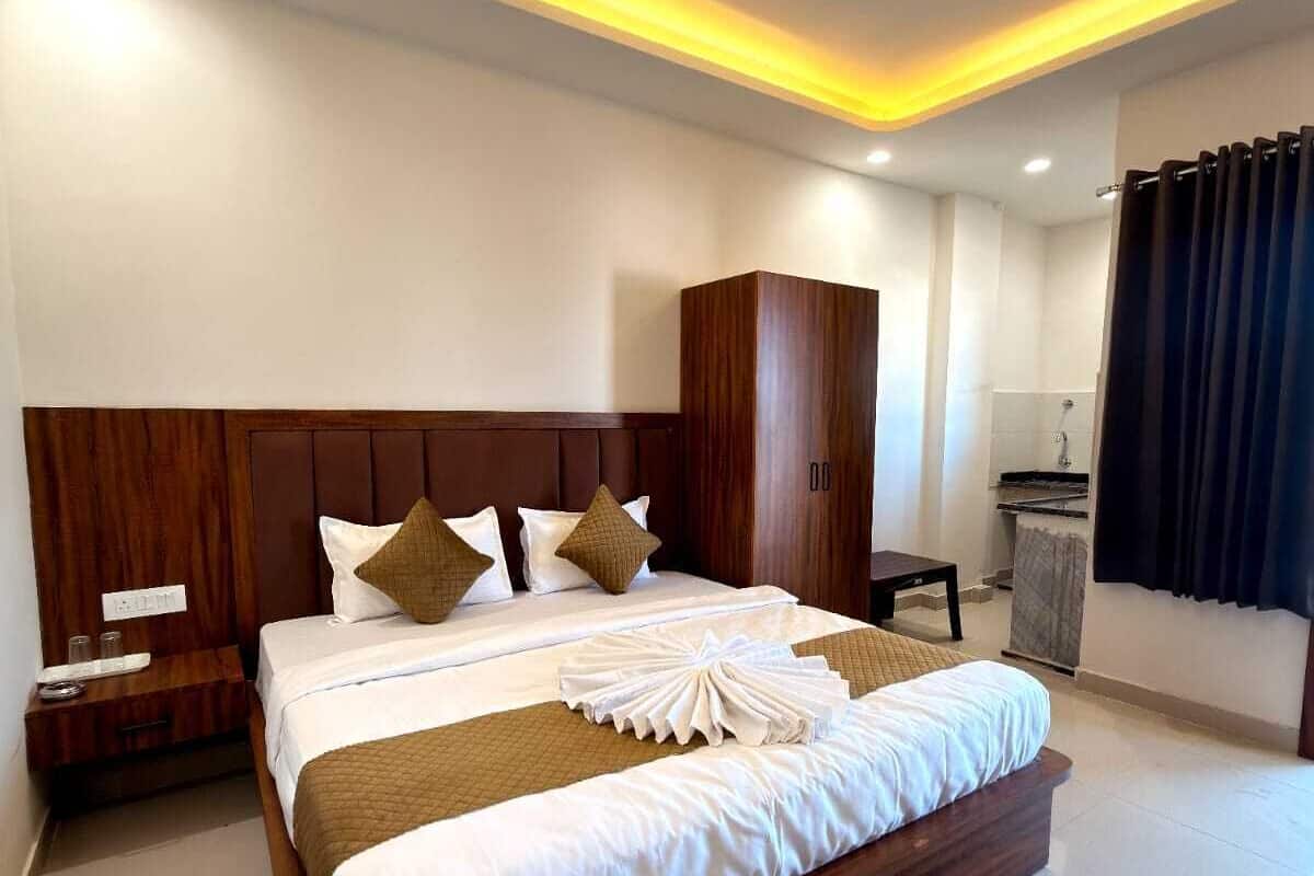 A hotel room with a large bed, a wardrobe, a desk, and a ceiling fan.