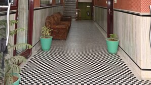 A hotel hallway with patterned walls, checkered flooring, and potted plants. - 45 room  family room and corporate (724)