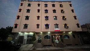 A multi-story hotel with a central entrance, a staircase leading to the main entrance, and a parking area in front. - 45 room  family room and corporate (724)