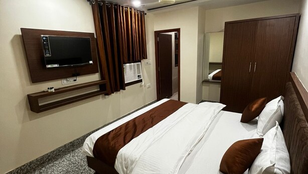 A hotel room with a bed, a TV mounted on the wall, a wardrobe, and a ceiling fan. - 45 room  family room and corporate (724)