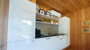 A modern kitchen with white cabinets, a black countertop, and a wooden ceiling. - Holiday Home in Otterlo With Terrace (Otterlo)