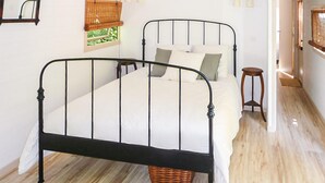 A bedroom with a metal bed frame, white bedding, a wooden floor, and a small wooden stool. - Amazing home in Aimargues (Aimargues)