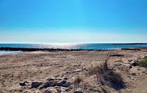 Ein sandiger Strand mit felsigem Ufer und blauem, klarem Himmel.
