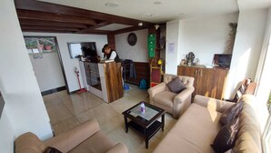 Un vestíbulo de hotel con mostrador de recepción, zona de estar y kitchenette.